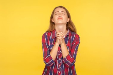 Lütfen, yalvarıyorum! Umutsuzluğa kapılmış, gömlekli, kollarını kaldırıp dua eden, başını kaldırıp yalvaran bir ifadeyle Tanrı 'ya yakaran kızıl kızın portresi. Stüdyo çekimi sarı arkaplanda izole edildi
