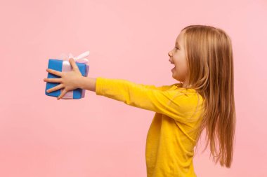 Al şunu! Cömert, sevimli küçük bir kızın hediye vermesi ve doğum gününü, anneler gününü kutlaması, hayır işi için hediye kutusu sunması. Pembe arka planda kapalı stüdyo çekimleri