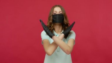 Siyah hijyenik yüz maskeli ve eldivenli kadın ellerini çapraz yapıp, bulaşıcı hastalıklar, solunum virüsü koronavirüsü 2019-ncov, grip salgını hakkında uyarıda bulunuyor. kırmızı arkaplanda izole