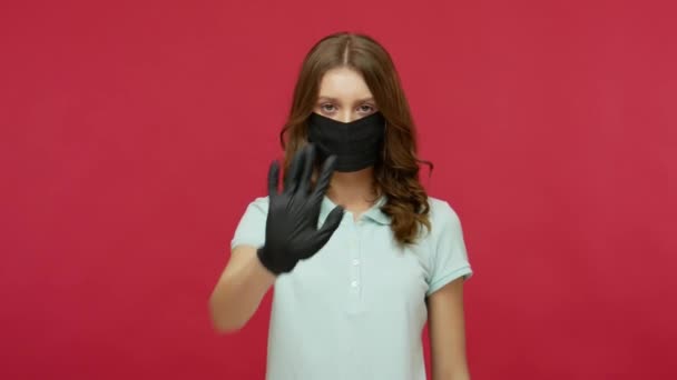 黒い衛生的な顔のマスクと手袋のジェスチャーストップで若い女性が手を上げ 伝染病 呼吸器ウイルスのコロナウイルス2019 インフルエンザの流行について警告します 赤の背景に隔離され — ストック動画