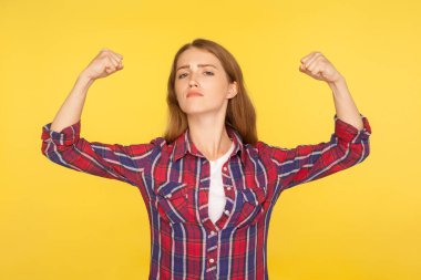 Ben güçlü bir kadınım! Kendine güveni olan, rahat gömlekli, güç ve güç gösteren, bağımsız başarılı hisseden, feminizm konsepti olan bir kızın portresi. Stüdyo çekimi, sarı arkaplan