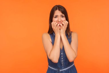 Tırnak yiyen esmer, korkmuş bir kadın korkmuş sinirli bir ifadeyle kameraya bakıyor obsesif kompulsif bozukluk ve anksiyete yaşıyor. Turuncu arka planda kapalı stüdyo çekimleri