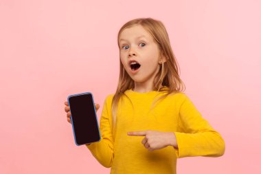Vay canına, cep telefonuna bak! Şok olmuş suratıyla kameraya bakan, cep telefonu reklamları, çocuk servisi, basit uygulamalar yapan hayret verici küçük kız. Stüdyoda çekim izole edildi