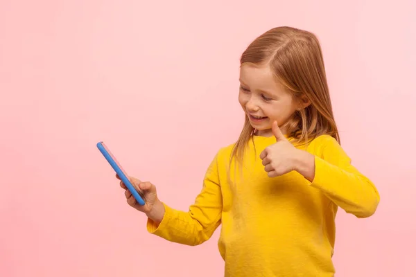 Retrato Niña Emocionada Sonriendo Haciendo Gestos Con Pulgar Hacia Teléfono —  Fotos de Stock