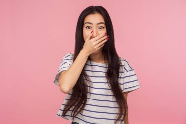 Omg, hiçbir şey söylemeyeceğim! Çizgili tişörtlü, ağzı kapalı, korkmuş gözlerle bakan, gerçeği söylemekten korkan korkmuş bir kızın portresi. Stüdyo çekimi pembe arkaplanda izole edildi