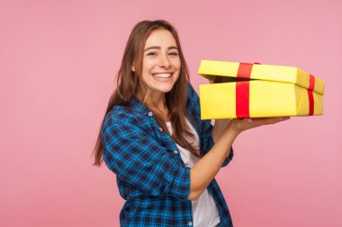 Güzel bayram hediyesi, bonus! Kareli tişörtlü, paketlenmemiş bir kutuyla mutlu güzel bir kızın portresi. Dişli bir gülümsemeyle kameraya bakıyor. Doğum günü hediyesi için heyecanlanıyor. Stüdyoda çekim izole edildi