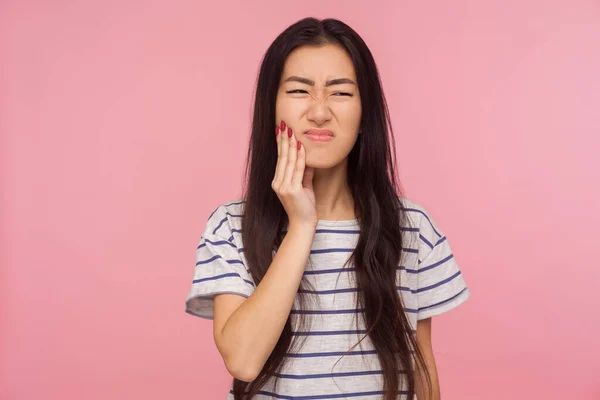 口腔卫生 有黑发女孩的画像 条纹T恤 触摸下巴 感觉牙痛 在可怕的痛苦中鬼鬼祟祟 牙齿问题 在粉红背景下隔离的室内拍摄 — 图库照片