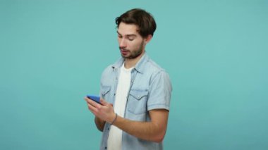 Mobil iletişim. Kot pantolonlu, ciddi sakallı bir adam cep telefonuna mesaj yazıyor, blog okuyor, bilgi üzerinde düşünüyor, seçim yapıyor, şüpheleri var. Kapalı stüdyo çekimi, izole.