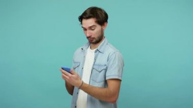 Mobil iletişim. Sakallı adam cep telefonundan gelen mesaja hayretle bakıyor, blog okuyor ve aniden şok edici bilgiler buluyor, haberlere şaşırıyor. Kapalı stüdyo çekimi, izole.