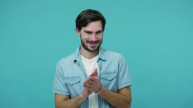 Kot pantolonlu, sinsi, entrikacı, sakallı adam ellerini ovuşturuyor, kurnaz fikirler kurcalıyor, sırıtıyor ve komplo kuran kötü adam planıyla aç gözlü sinsi bir ifadeyle bakıyor. Stüdyo çekimi mavi arkaplanda izole edildi