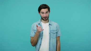 Çağrı merkezi konsepti, telefonla iletişim. Kot pantolonlu, sakallı, olumlu bir adam bana jest yapıyor ve telefonla konuşuyor. Mavi arka planda kapalı stüdyo çekimleri