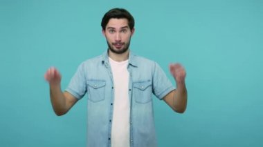 Reklamlara bak! Pozitif adam aşağı işaret ediyor, abone olmamı söylüyor, el kol hareketi yapıyor ve reklam amaçlı bilgi veriyor. Stüdyo çekimi mavi arkaplanda izole edildi
