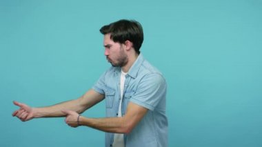 Kot pantolonlu genç sakallı erkek işçi görünmez halatla ağır yük çekiyor, motive olmuş görünüyor, büyük çaba sarf ediyor, amaca ulaşmak için çabalıyor. Stüdyoda çekim izole edildi