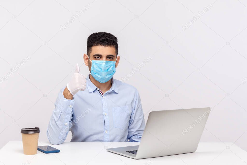 Businessman wearing hygienic mask and gloves, showing thumb up, recommending effective protect filter to prevent contagious disease coronavirus, 2019-nCoV, flu epidemic. indoor studio shot, white background