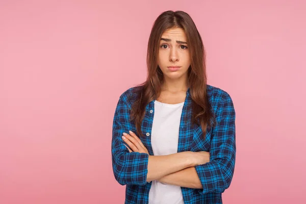 Portrait of displeased unhappy brunette girl in bad mood looking at camera with resentful vexed face and holding hands crossed, worried about failure. indoor studio shot isolated on pink background