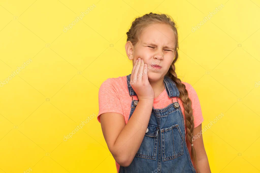 Dolor dental en niños. Retrato de una niña malsana con trenza en un