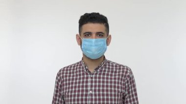 Tıbbi maske takan ve baş parmak işareti yapan mutlu bir adam. Solunum viral enfeksiyonlarına karşı mükemmel bir koruma öneriyor. Koronavirüs 2019-nCoV 'un önlenmesi. Kapalı stüdyo çekimi, izole.