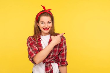 Bak, reklam! İyimser çekici kızın portresi gülümseyen ve boş duvara işaret eden, ticari metin için kopya alanı gösteren. 50 'li yılların modası, kapalı stüdyo çekimleri, izole edilmiş.