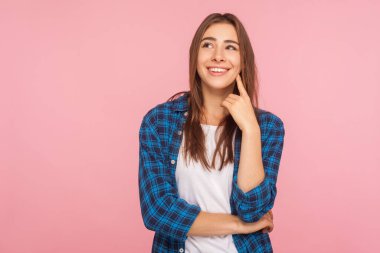 Kareli tişörtlü neşeli hayalperest kızın portresi. Olumlu bir şeyler hayal ediyor ve gülümsüyor. Hoş anıları düşünüyor, dilek tutuyor, fantezi kuruyor. Pembe arka planda kapalı stüdyo çekimleri