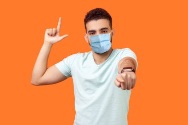 Sen kaybedensin! Beyaz tişörtlü, sinirli ve patronluk taslayan bir adamın portresi. Ezik hareketini gösteriyor ve kamerayı gösteriyor. Yenilginle dalga geçiyor. Turuncu arka planda kapalı stüdyo çekimleri