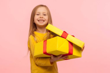 İyi bir hediyeyle tatmin olmuş bir çocuk. Küçük sevimli bir kızın portresi hediye kutusunu açıyor ve kameraya gülümsüyor, doğum gününü kutluyor, Noel tatilini kutluyor. Stüdyo çekimi pembe arkaplanda izole edildi