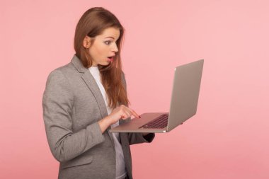 Bilgisayarda yazı yazan ve hayret verici bir ifadeyle bakan ofis çalışanının portresi, çalışmak için bilgisayar kullanan iş kadını, online çalışan, uygulamadan şok olan. Stüdyo çekimi pembe arkaplanda izole edildi