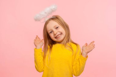 Oyuncu melek gibi küçük kız kollarını kaldırıyor ve kameraya dişlek bir gülümsemeyle bakıyor, el kol hareketi yapıyor, bilmiyorum, ben değildim, neşeli çocuk suçunu inkar ediyordu. Pembe arka planda kapalı stüdyo çekimleri