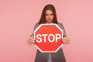 Giriş yasak, kesinlikle yasak! Kırmızı trafik dur işareti taşıyan esmer kadının portresi tehlike uyarısı, kısıtlama ve sınırlar, yol işaretine odaklan. Stüdyo çekimi pembe arkaplanda izole edildi