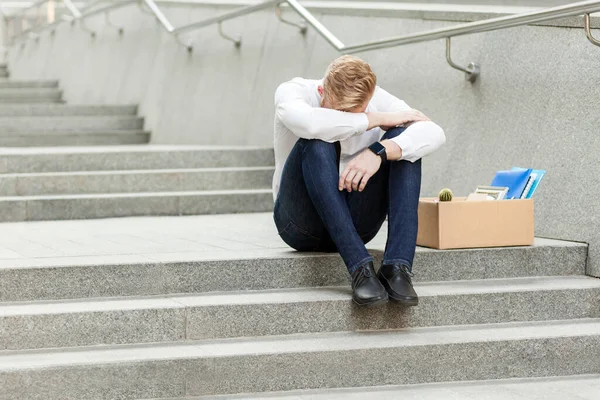 İşini kaybetti, genç adam merdivenlerde oturup başını eğip depresyona girdi, ağladı ve kriz anında ne yapacağını bilemedi. Daha gevşek hissediyorum. Açık hava çekimi. işletme ve sağlık hizmetleri kavramı.