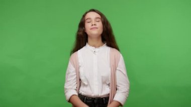 Ahenk ve barış. Beyaz gömlekli çekici esmer kız dua jestinde el ele tutuşup yoga meditasyonu yapıyor, sakin ve dengeli hissediyor. Yeşil arka planda izole edilmiş kapalı stüdyo çekimi