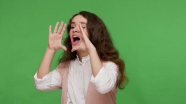 Dikkat, önemli reklam! Beyaz tişörtlü, el ele tutuşan, ağzı açık, bağıran, bağıran tatlı esmer kız. Stüdyo çekimi yeşil arkaplanda izole edildi