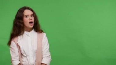 Vay canına, reklama bak! Şaşırmış genç esmer kız, ticari metin için boş bir yer göstererek, reklam görüntüsü için çalışma alanı hazırlıyor. Stüdyo çekimi yeşil arkaplanda izole edildi