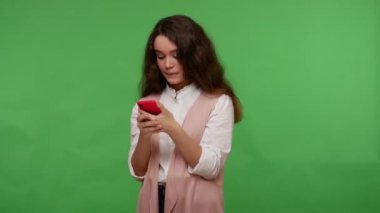 Cep telefonundan mesaj okuyan, sosyal ağlarda arkadaşlarıyla sohbet eden, mobil uygulama kullanan, online sipariş veren sevimli bir genç kız. Yeşil arka planda izole edilmiş kapalı stüdyo çekimi