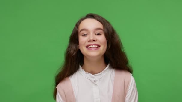 迷人的少年黑发女孩 穿着白色经典衬衫 笑相机 看起来无忧无虑和善良 表达积极的情感 在绿色背景下隔离的室内拍摄 — 图库视频影像