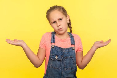 Bilmiyorum! Bilmiyorum! Kot pantolon giymiş, güvenilmez küçük bir kızın portresi sorgulama jesti ile el kaldırıyor, cevaptan emin değil, şüphelerini dile getiriyor. Sarı arka planda izole edilmiş kapalı stüdyo çekimi