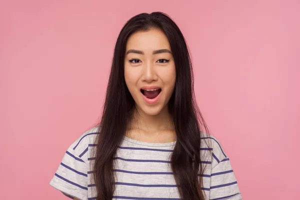 Wow, unbelievable story! Portrait of amazed girl with long brunette hair in striped t-shirt keeping her mouth opened and looking with surprised face. indoor studio shot isolated on pink background