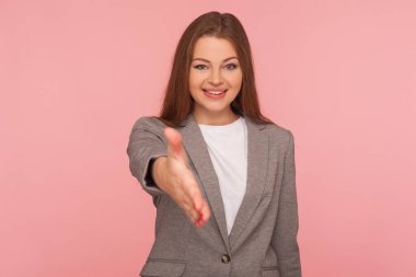 Merhaba, tanıştığımıza memnun oldum! İş elbisesi giymiş bir kadının portresi tokalaşıyor ve gülümsüyor arkadaşça, danışman ya da İK yöneticisi iş teklif ediyor, ortaklık teklif ediyor. Stüdyo çekimi pembe arkaplanda izole edildi