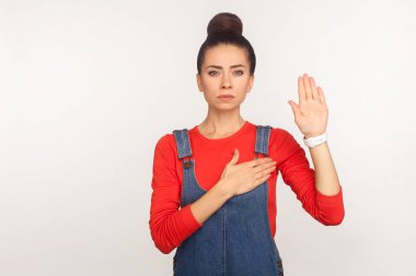 Söz veriyorum. Kot pantolon giymiş güvenilir dürüst bir kızın portresi sadakat yemini etmek için elini kaldırıyor sorumluluk sahibi ve vatansever bir insan. Beyaz arka planda izole edilmiş kapalı stüdyo çekimi
