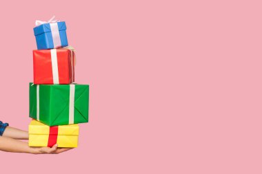 Bir sürü hediye paketi tutan kadın eller, pembe arka plana karşı bir sürü Noel hediyesi mağaza primleri ve satışlar hakkında bilgi almak için fotokopi alanı, indirimler. Kapalı stüdyo çekimi, izole.