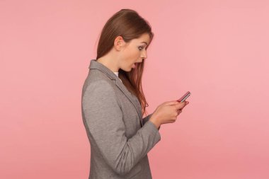 Takım elbiseli zarif bayan patronun mesajları okurken şaşkınlığını dile getirmesi, akıllı telefondan inanılmaz şok edici haberleri kontrol etmesi, mobil iş uygulaması kullanması. Stüdyo çekimi izole