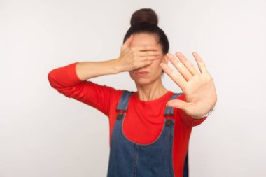 - Hayır, bakmak istemiyorum! Tişörtlü, kot pantolonlu, gözleri elle kaplayan ve dur hareketi yapan, izlemekten kaçınan mutsuz bir kızın portresi. Beyaz arka planda izole edilmiş kapalı stüdyo çekimi