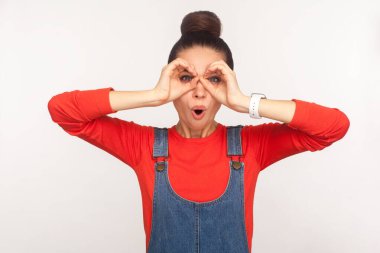 Kot pantolonlu, şaşkın bir kızın portresi dürbünlü el hareketlerine bakıyor, inanılmaz bir şey keşfediyor, hayrete düşürüyor. Stüdyoda çekim izole edildi