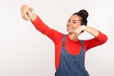 Blog 'a üye ol! Moda tarzı bir kızın portresi kot pantolonlu, cep telefonunda video bloğu yayınlayan ve takip etmeyi öneren şık bir kız. Beyaz arkaplan, kapalı stüdyo çekimleri