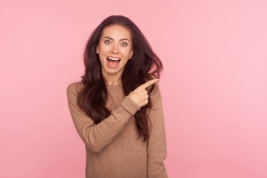 Vay canına, reklamcılığa dikkat! Şaşırmış, esmer saçlı genç bir kadının portresi ticari metinler için fotokopi alanı gösteriyor. Fikir sunumlu boş bir duvar. Stüdyo çekimi