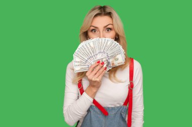 Banka mevduatı, para kârı. Şık tulumlu, şaşaalı yetişkin bir kadının portresi. Büyük gözlü, şaşaalı bir ifadeyle dolar banknotlarından gizlice bakıyor. Yeşil arka planda izole edilmiş kapalı stüdyo çekimi
