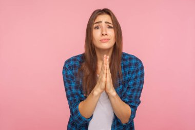 Ne olur! Kareli gömlekli bir kızın portresi dua ederken el ele tutuşuyor, yalvaran bir ifadeyle bakıyor, yardım dileniyor, af diliyor. Pembe arka planda kapalı stüdyo çekimleri