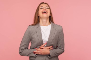 Portrait of happy carefree young woman in business suit holding her belly and laughing loud at joke, amused by funny anecdote, enjoying positive emotions. studio shot isolated on pink background clipart