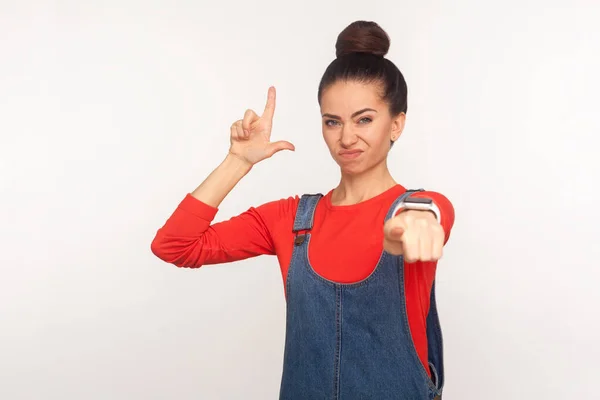 Portrait Irritated Girl Hair Bun Denim Overalls Showing Loser Gesture — Stock Photo, Image