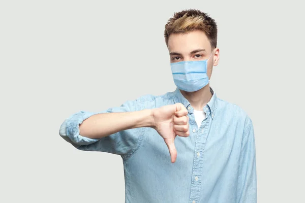 Niechęć Portret Niezadowolonego Młodego Człowieka Chirurgicznej Masce Medycznej Jasnoniebieskiej Koszuli — Zdjęcie stockowe