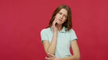 Diş ağrısı, diş sorunları. Polo tişörtlü, yanağına dokunan, diş çürüğü, çene ağrısı ve sakız hastalığından muzdarip esmer bir kadının portresi. Kırmızı arkaplanda izole edilmiş kapalı stüdyo çekimi